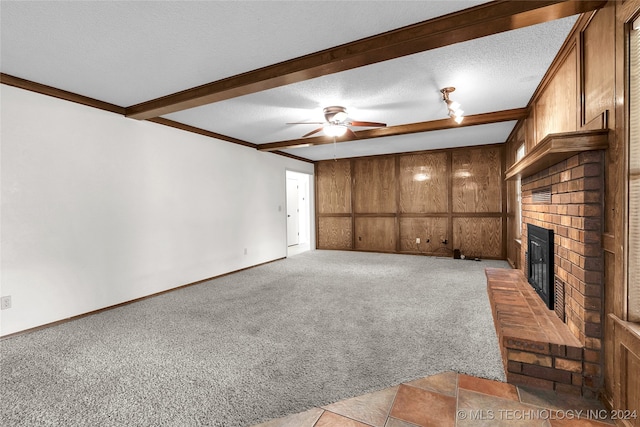 unfurnished living room with a textured ceiling, beam ceiling, light colored carpet, a brick fireplace, and ceiling fan