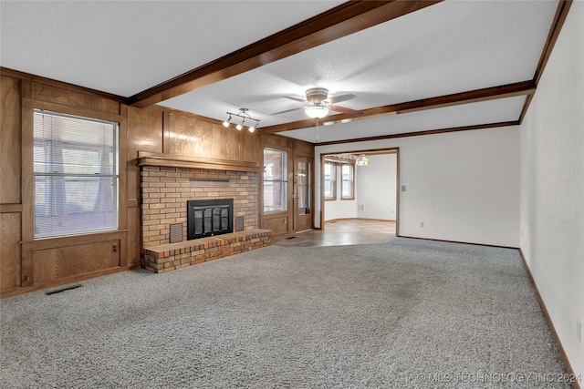 unfurnished living room featuring beam ceiling, ceiling fan, light colored carpet, and a brick fireplace