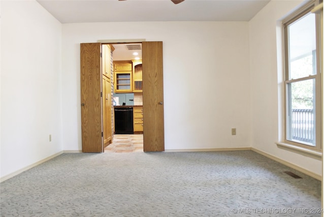 unfurnished room with visible vents, ceiling fan, light colored carpet, and baseboards