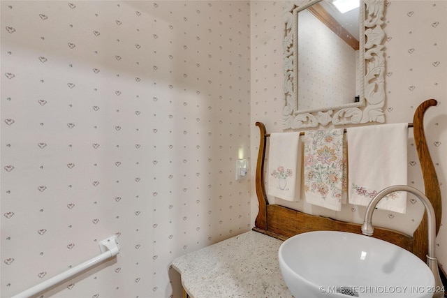 bathroom featuring a sink and wallpapered walls