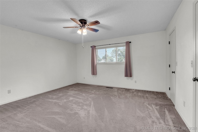 spare room featuring light carpet, ceiling fan, and a textured ceiling