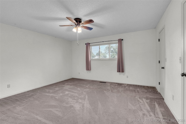 carpeted spare room featuring a textured ceiling and a ceiling fan