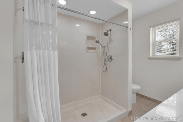 bathroom featuring tile patterned flooring, toilet, and a shower with curtain