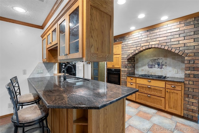 kitchen featuring glass insert cabinets, oven, a sink, ornamental molding, and a kitchen breakfast bar