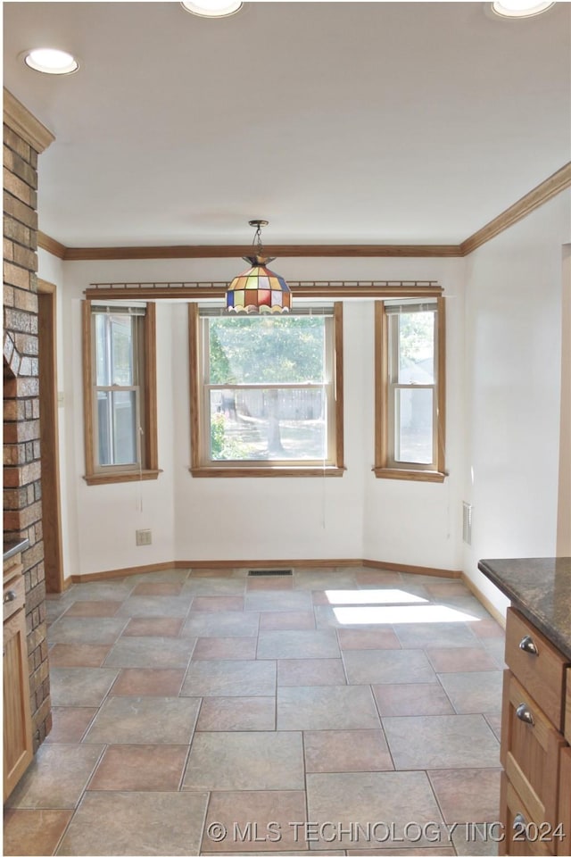 unfurnished dining area with ornamental molding, baseboards, visible vents, and stone finish flooring