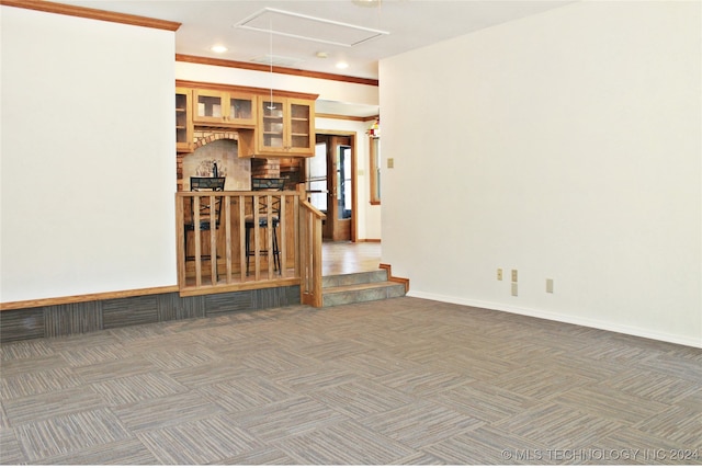 unfurnished room with dark carpet, bar, and ornamental molding