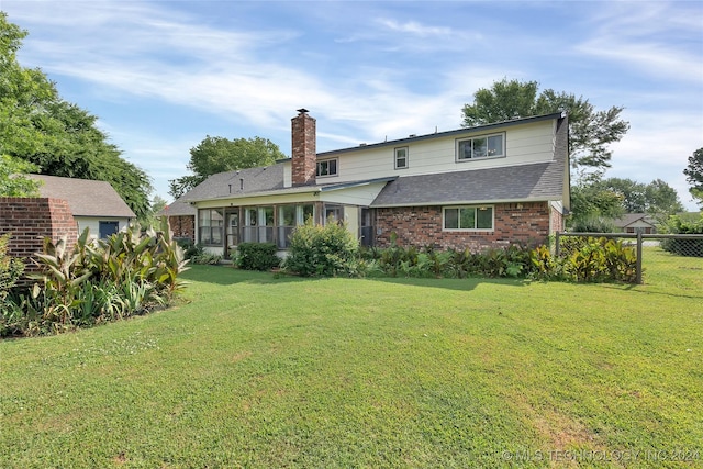 back of house with a yard, fence, brick siding, and a shingled roof