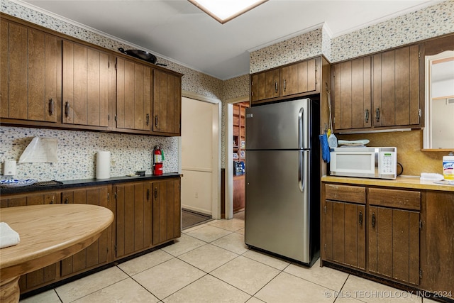 4108 S Saint Louis Ave, Tulsa, OK 74105 - kitchen with freestanding refrigerator, white microwave, wallpapered walls, light tile patterned floors, and dark brown cabinetry