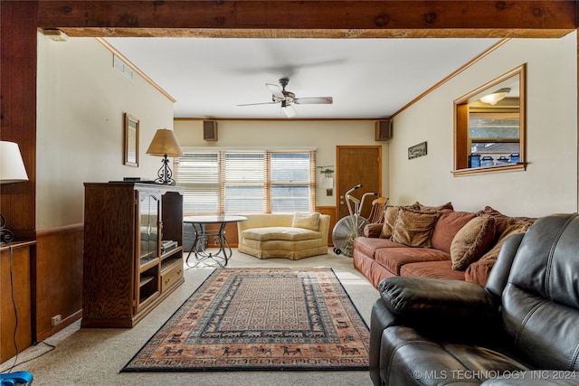 living room with wood walls, beamed ceiling, crown molding, ceiling fan, and light colored carpet