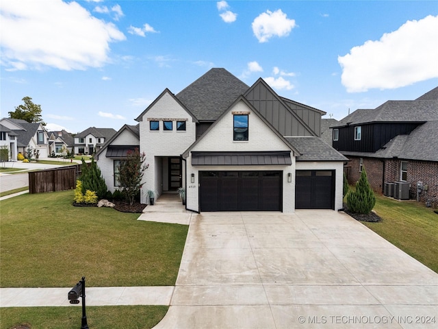 view of front of property with a garage, a front lawn, and central AC unit