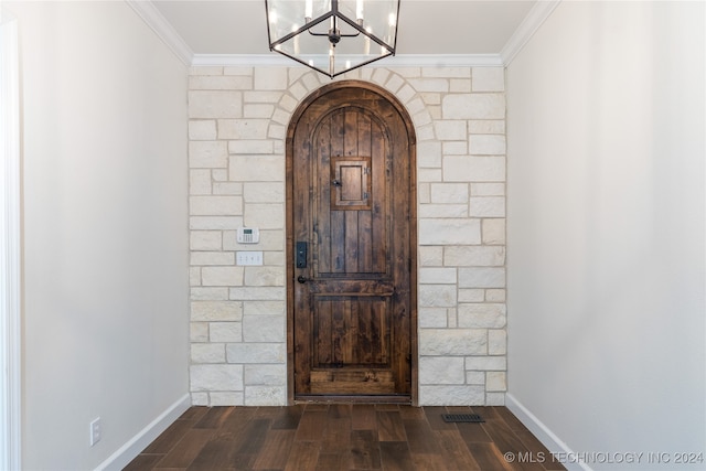 interior space with ornamental molding, an inviting chandelier, and dark wood-type flooring