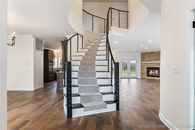 staircase with french doors, a fireplace, crown molding, and hardwood / wood-style floors