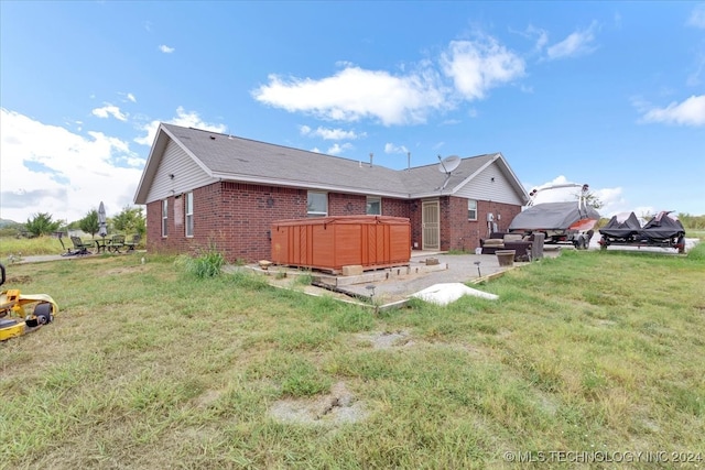 rear view of house featuring a hot tub, a patio area, and a yard