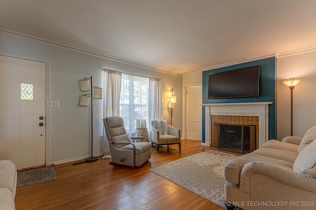 living room featuring a tile fireplace, wood-type flooring, and crown molding