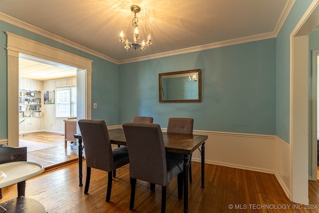 dining area with ornamental molding, an inviting chandelier, and hardwood / wood-style flooring