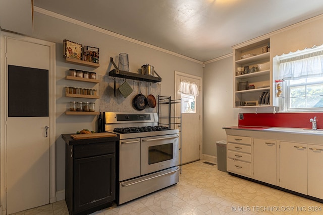 kitchen with white cabinets, ornamental molding, stainless steel range with gas cooktop, and a healthy amount of sunlight