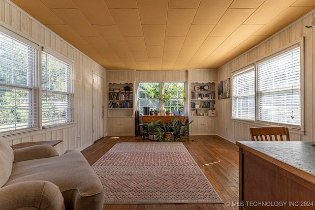 living room featuring wood-type flooring, wooden walls, and built in features