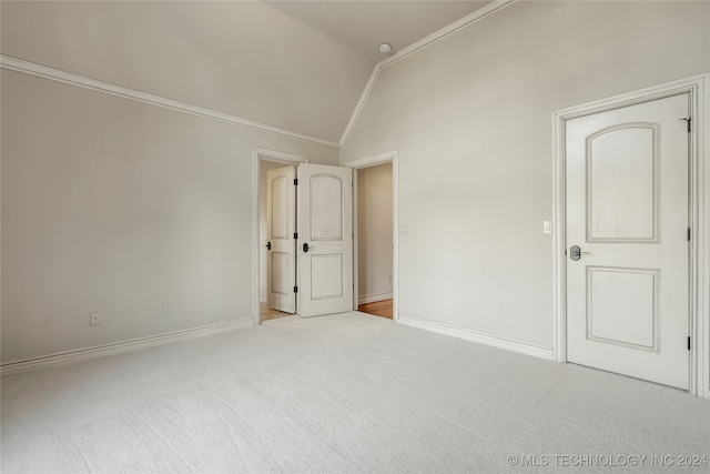 unfurnished bedroom featuring vaulted ceiling, light colored carpet, and crown molding