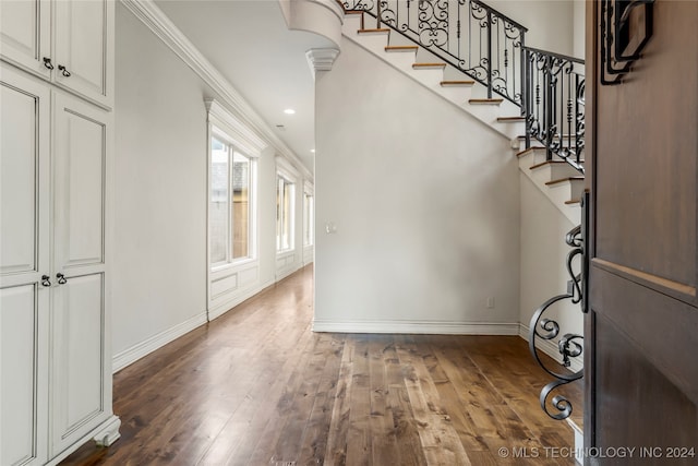 foyer entrance with dark wood-type flooring and ornamental molding