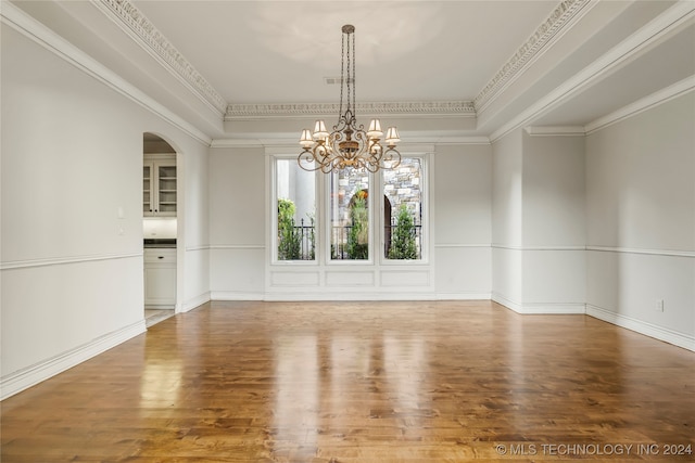 unfurnished room featuring wood-type flooring, an inviting chandelier, and ornamental molding