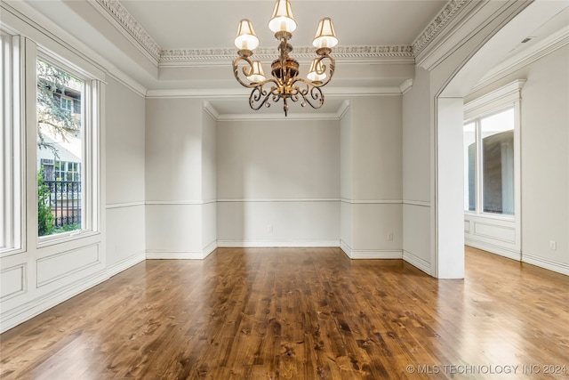 empty room featuring a notable chandelier, crown molding, and hardwood / wood-style floors