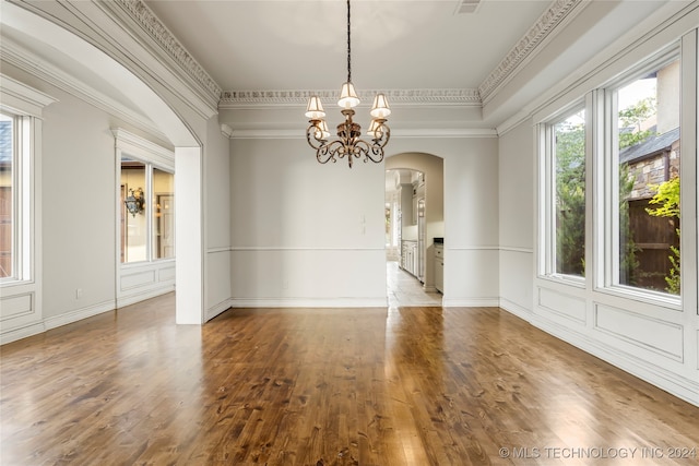 spare room with an inviting chandelier, wood-type flooring, and crown molding