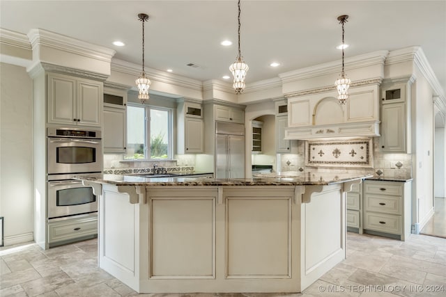 kitchen featuring a center island, appliances with stainless steel finishes, decorative light fixtures, crown molding, and dark stone countertops