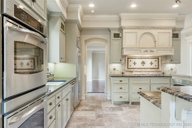 kitchen with dark stone countertops, cream cabinets, and appliances with stainless steel finishes