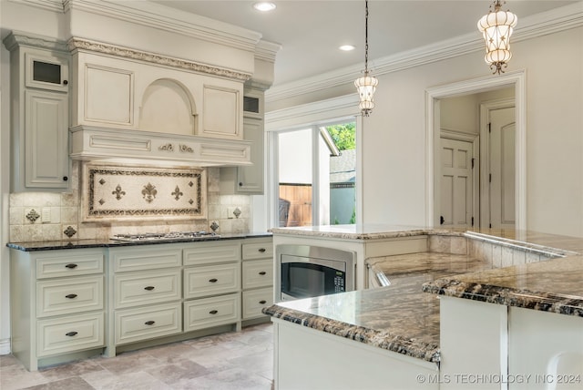 kitchen with tasteful backsplash, decorative light fixtures, cream cabinetry, appliances with stainless steel finishes, and dark stone countertops