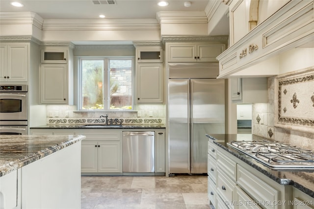 kitchen featuring decorative backsplash, stainless steel appliances, dark stone countertops, and custom range hood