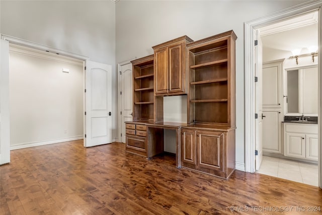 unfurnished office featuring a high ceiling, dark hardwood / wood-style floors, and sink