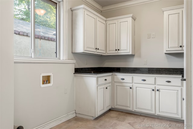 clothes washing area with hookup for a washing machine, ornamental molding, and cabinets