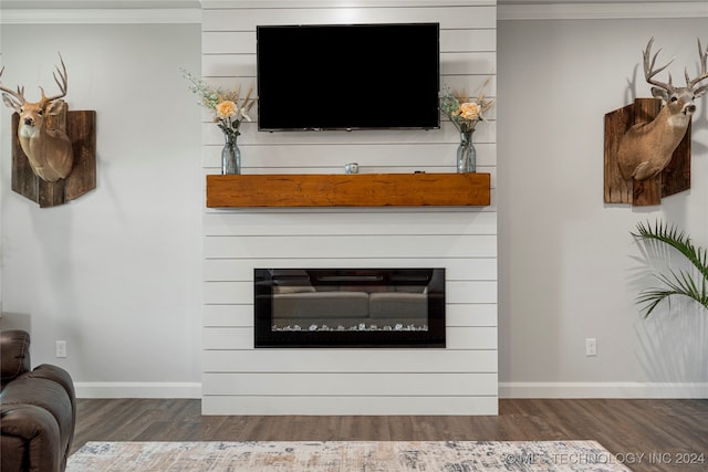 living room with baseboards, wood finished floors, a glass covered fireplace, and crown molding