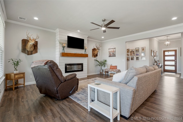 living room with ceiling fan with notable chandelier, a fireplace, ornamental molding, and dark hardwood / wood-style floors