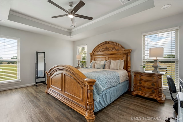 bedroom with dark wood finished floors, a raised ceiling, baseboards, and ornamental molding