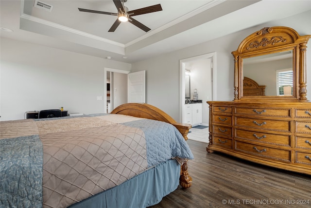 bedroom with a raised ceiling, connected bathroom, dark hardwood / wood-style flooring, crown molding, and ceiling fan