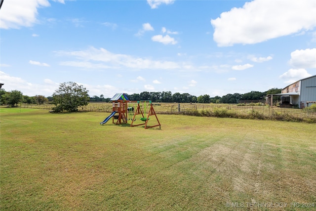 view of playground featuring a rural view, a yard, and fence