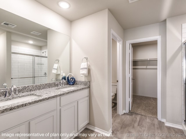 bathroom featuring wood-type flooring, vanity, toilet, and an enclosed shower