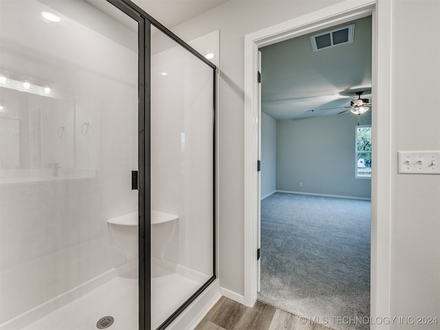 bathroom with hardwood / wood-style flooring, a shower with door, and ceiling fan