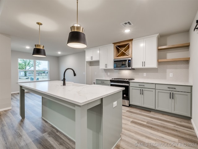 kitchen featuring light stone counters, light hardwood / wood-style flooring, sink, appliances with stainless steel finishes, and decorative light fixtures