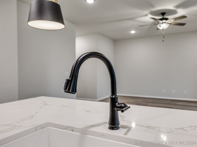 interior details featuring light stone counters, sink, and ceiling fan