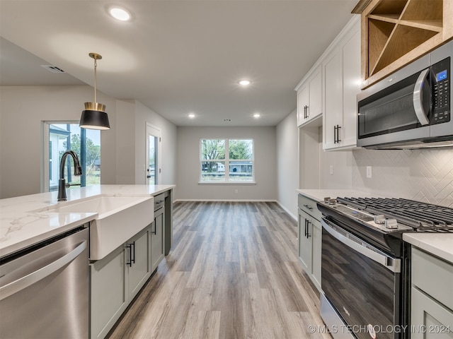 kitchen with light hardwood / wood-style floors, appliances with stainless steel finishes, decorative light fixtures, and a healthy amount of sunlight