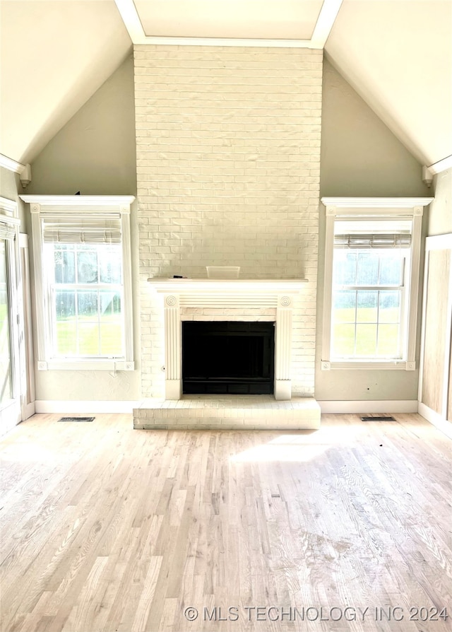 unfurnished living room featuring light hardwood / wood-style floors, lofted ceiling with beams, and a brick fireplace