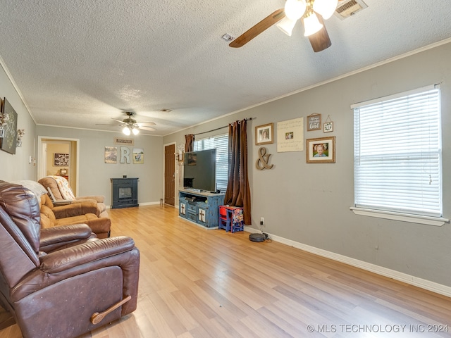 living room featuring a textured ceiling, light hardwood / wood-style floors, ornamental molding, and ceiling fan