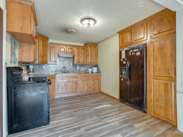 kitchen featuring light hardwood / wood-style floors, tasteful backsplash, range, sink, and black refrigerator with ice dispenser