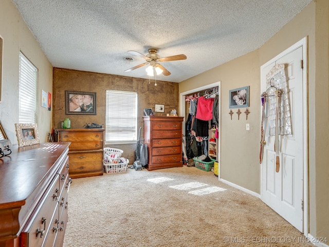 carpeted bedroom featuring a closet, ceiling fan, and a textured ceiling