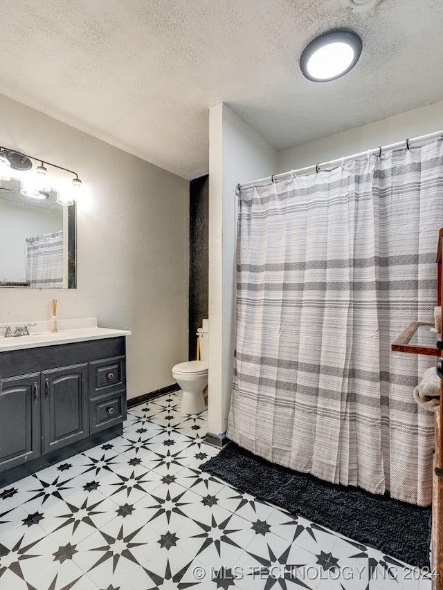 bathroom featuring a textured ceiling, vanity, and toilet