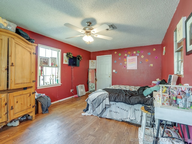 bedroom with a textured ceiling, light hardwood / wood-style floors, and ceiling fan