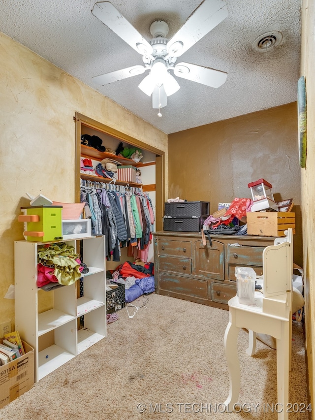 bedroom featuring ceiling fan, carpet floors, and a textured ceiling