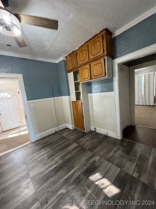 kitchen with a textured ceiling, crown molding, ceiling fan, and dark wood-type flooring